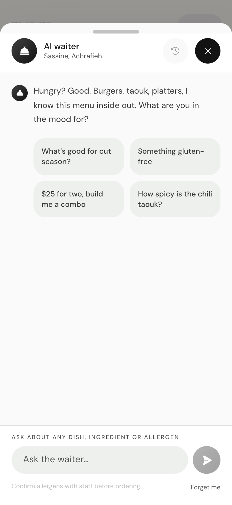 The AI waiter chat open on a phone, with a greeting, starter chips, and a message box